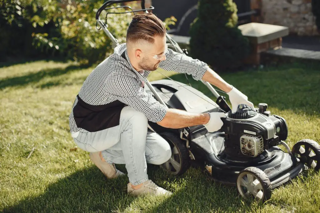man in black and white long sleeve shirt holding black lawn mower