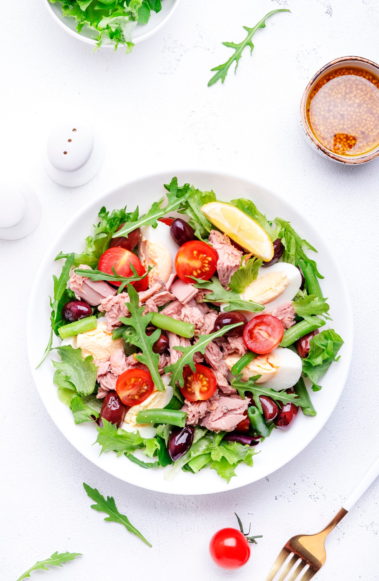 Nicoise salad with tuna, red tomatoes, boiled eggs, green beans and olives on plate