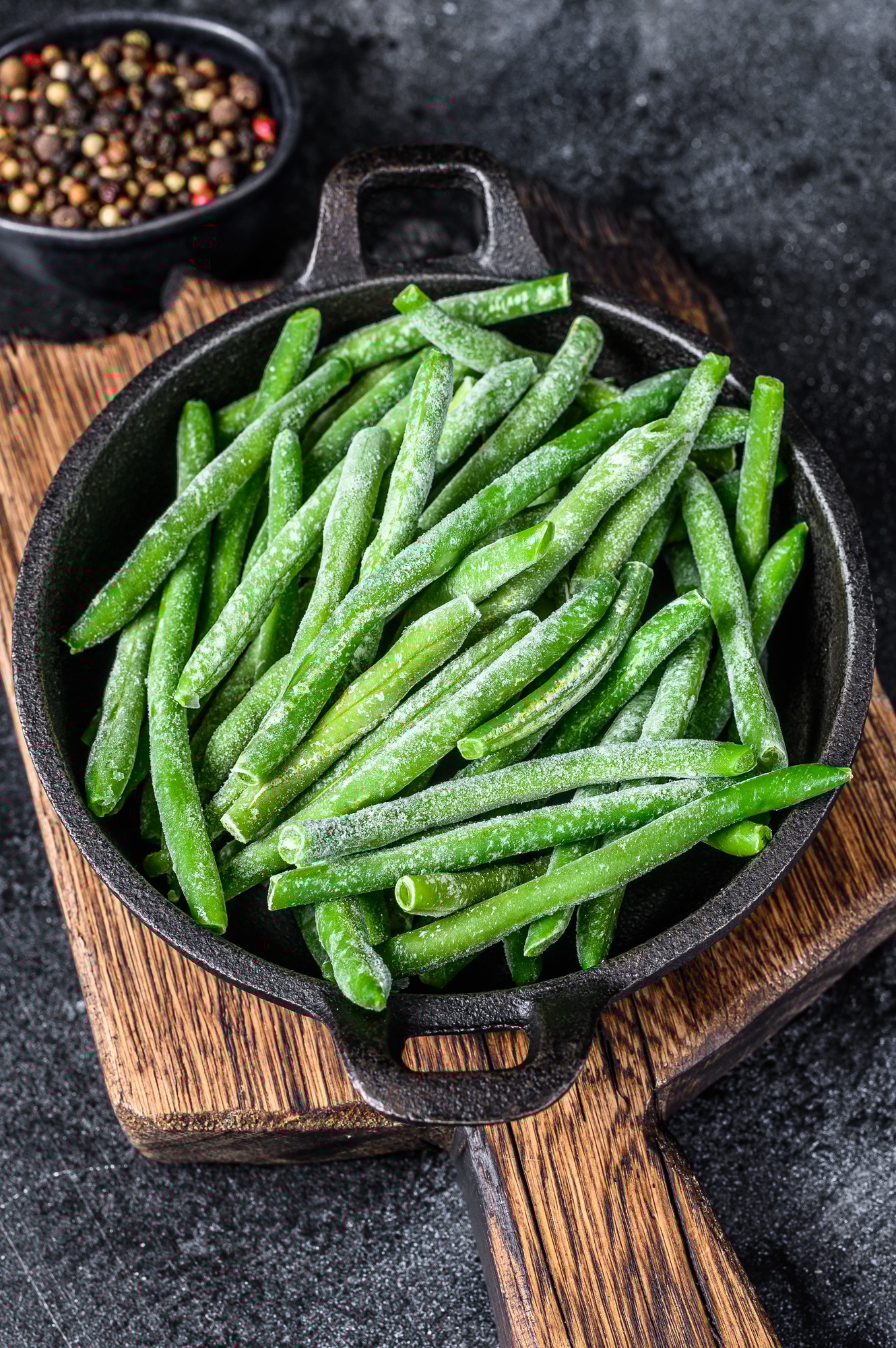 Frozen green beans in a pan. Black background. top view