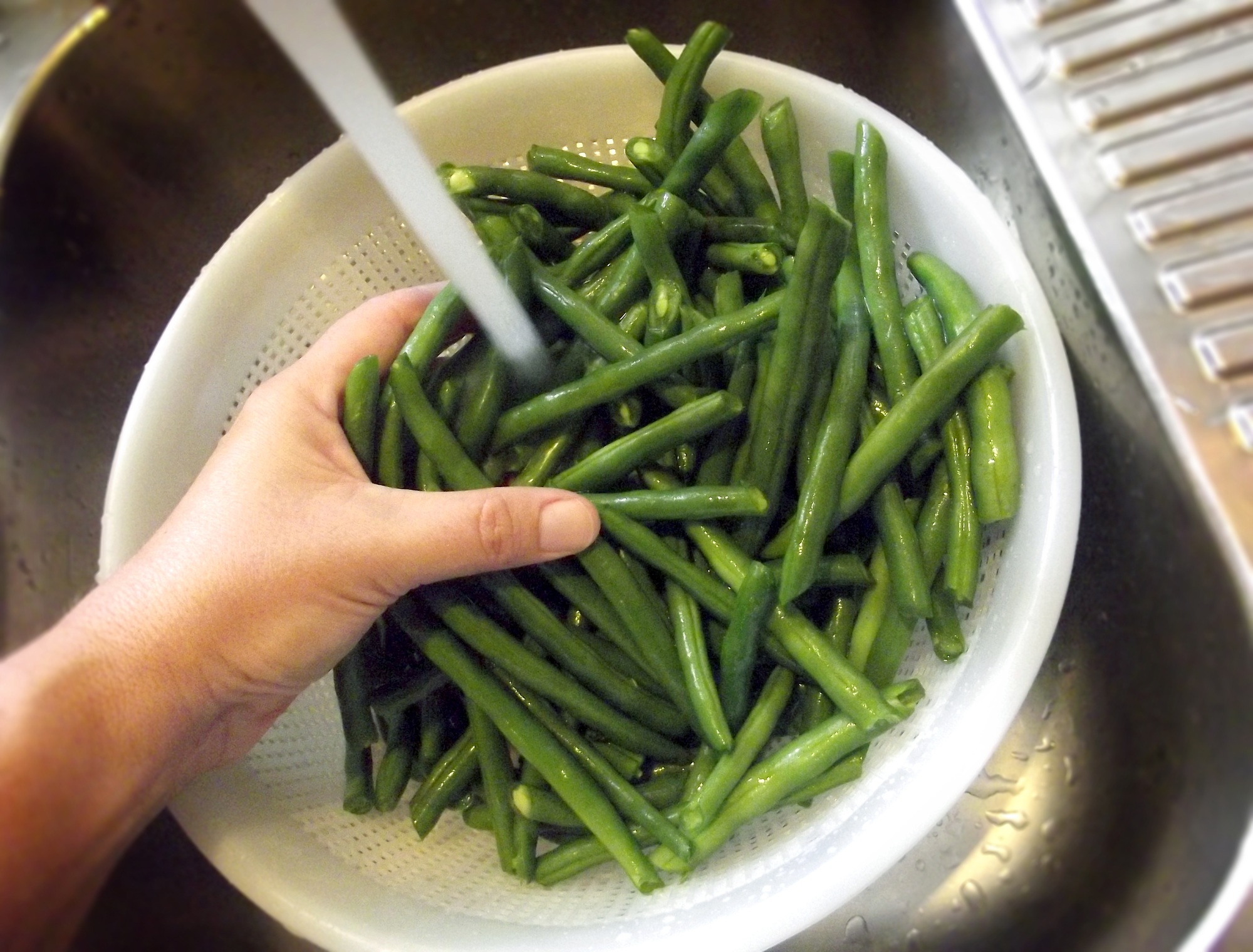 Washing green beans under water in the sink