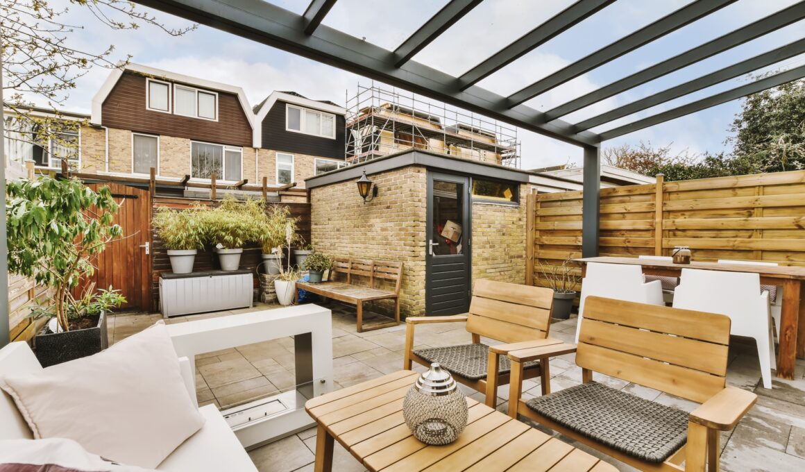 a backyard with wooden furniture and a privacy fence