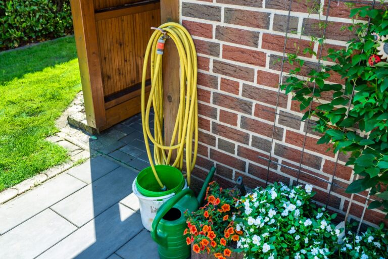 A garden yellow hose connected to a tap protruding from a farm building
