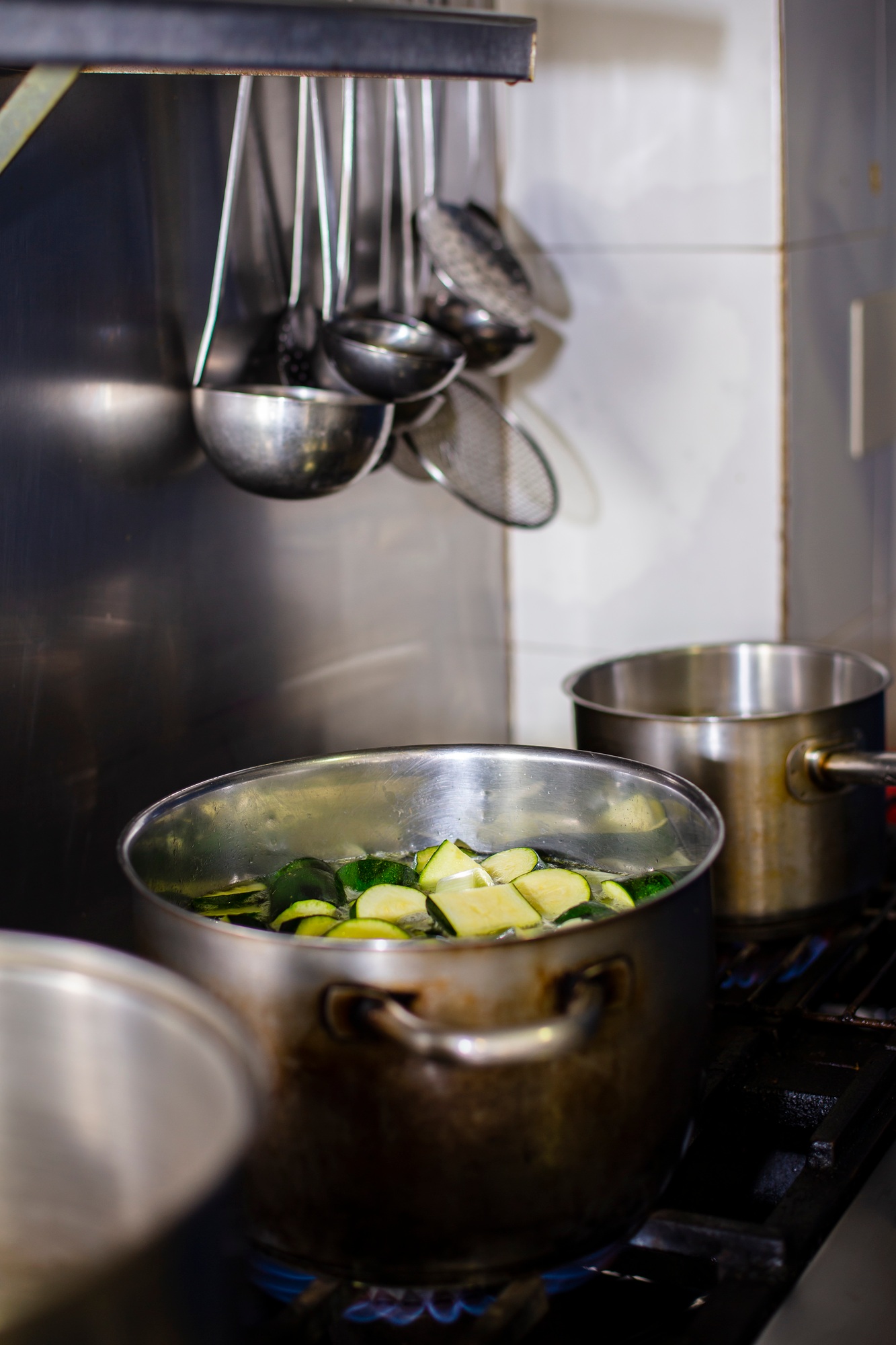 Boiling pot of zucchini for the preparation of a zucchini cream in a restaurant kitchen.
