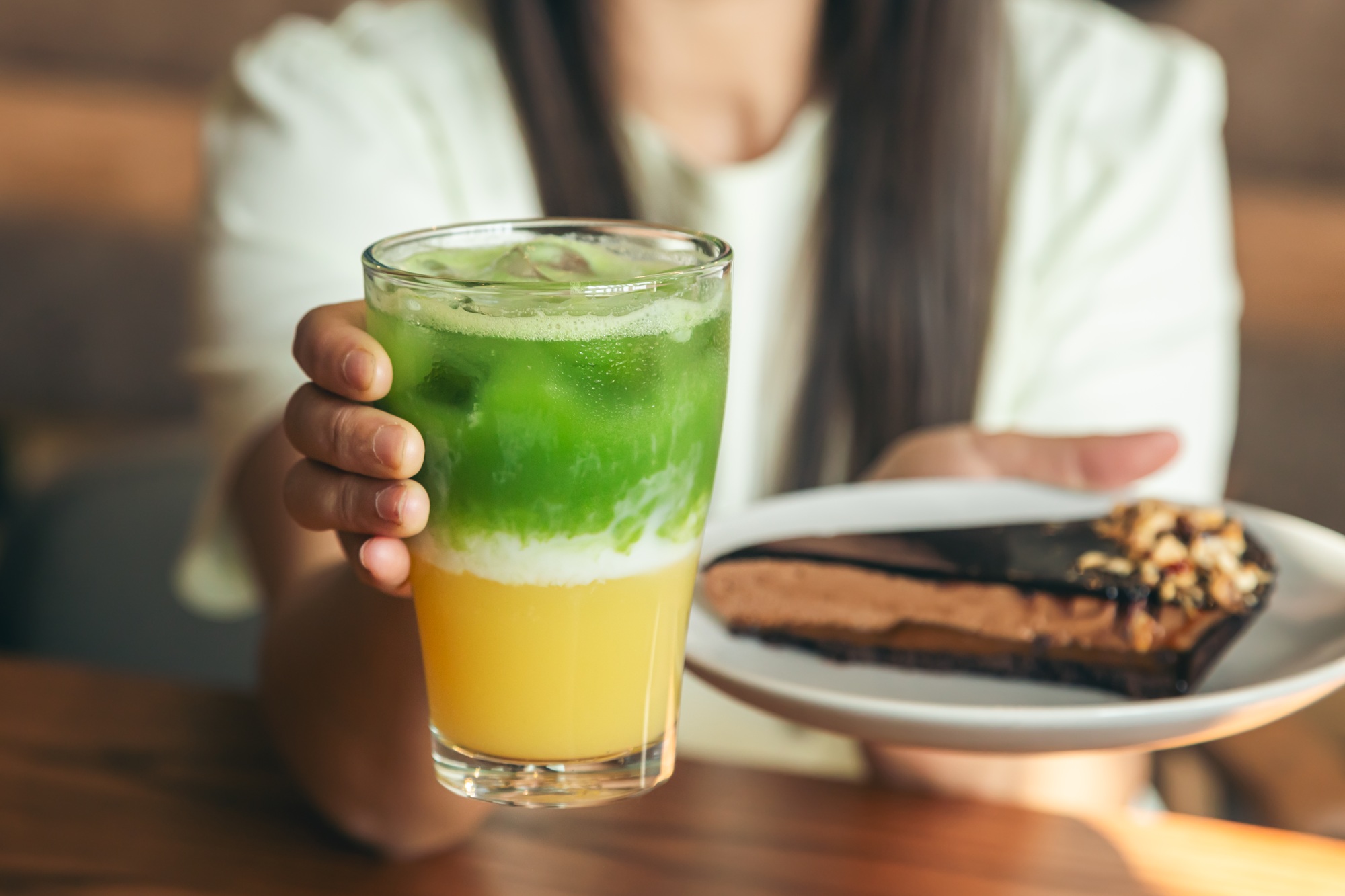 Close-up, lemonade and chocolate cake in female hands.