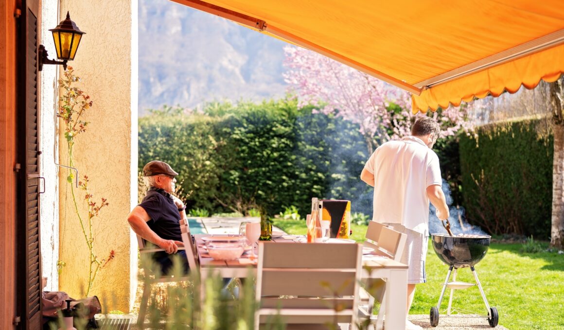 Guys time. Senior father and adult son enjoying barbecue on terrace of their summer house