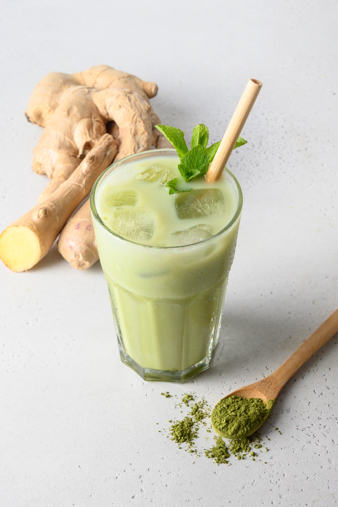 Iced Green matcha tea and pouring milk in latte glass on white table.
