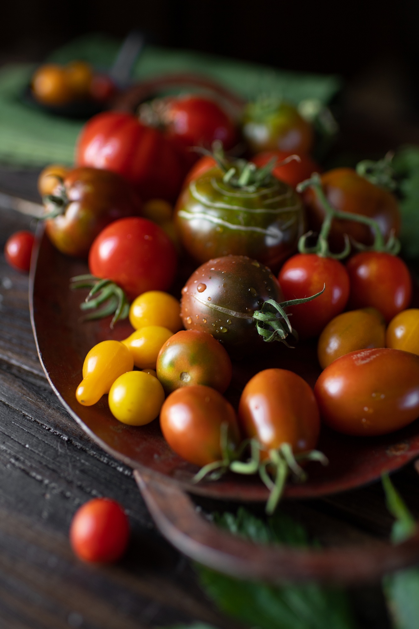 Still life, different varieties of tomato scattered on a wooden table, soft morning light, top view