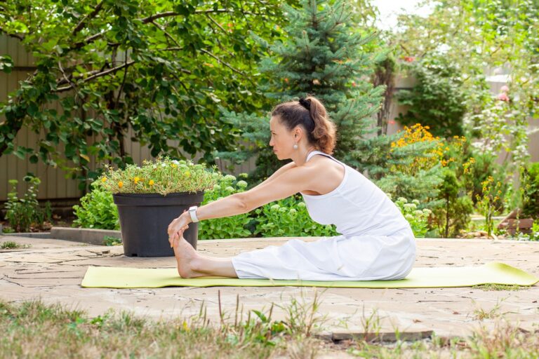 Young woman practices yoga in the courtyard of a country house.