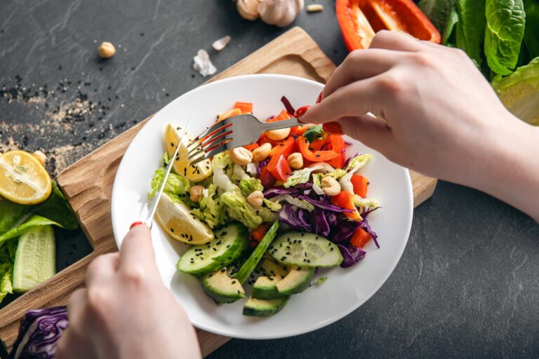 A woman eats a vegetarian salad of fresh vegetables, close-up of the plate.