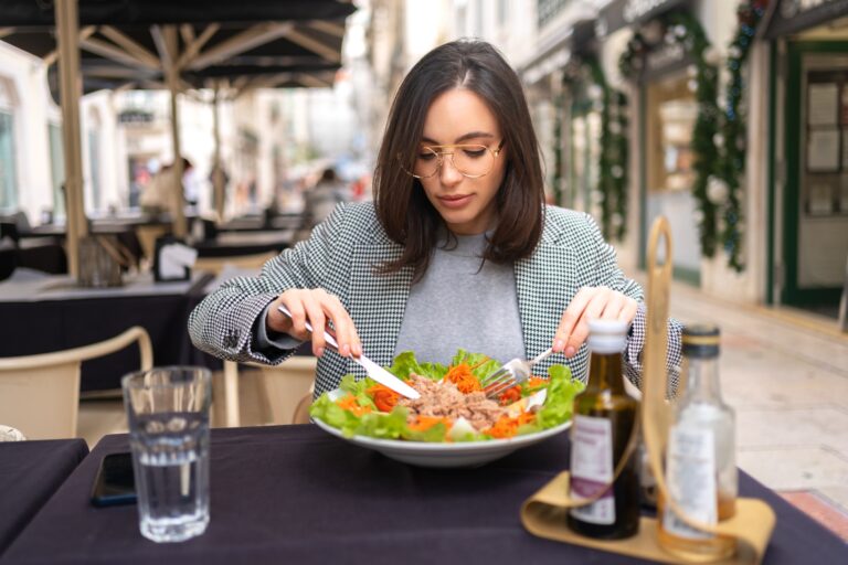 Woman eating healthy salad on restaurant terrace