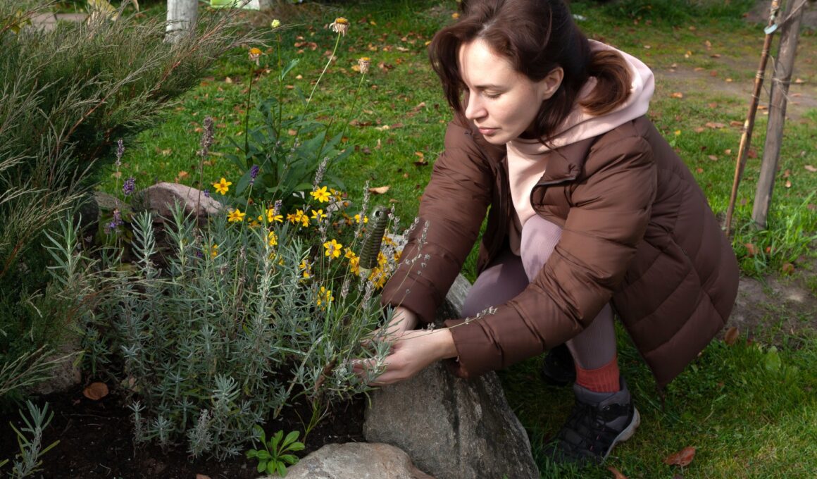 Young woman caring for flowers in flower bed