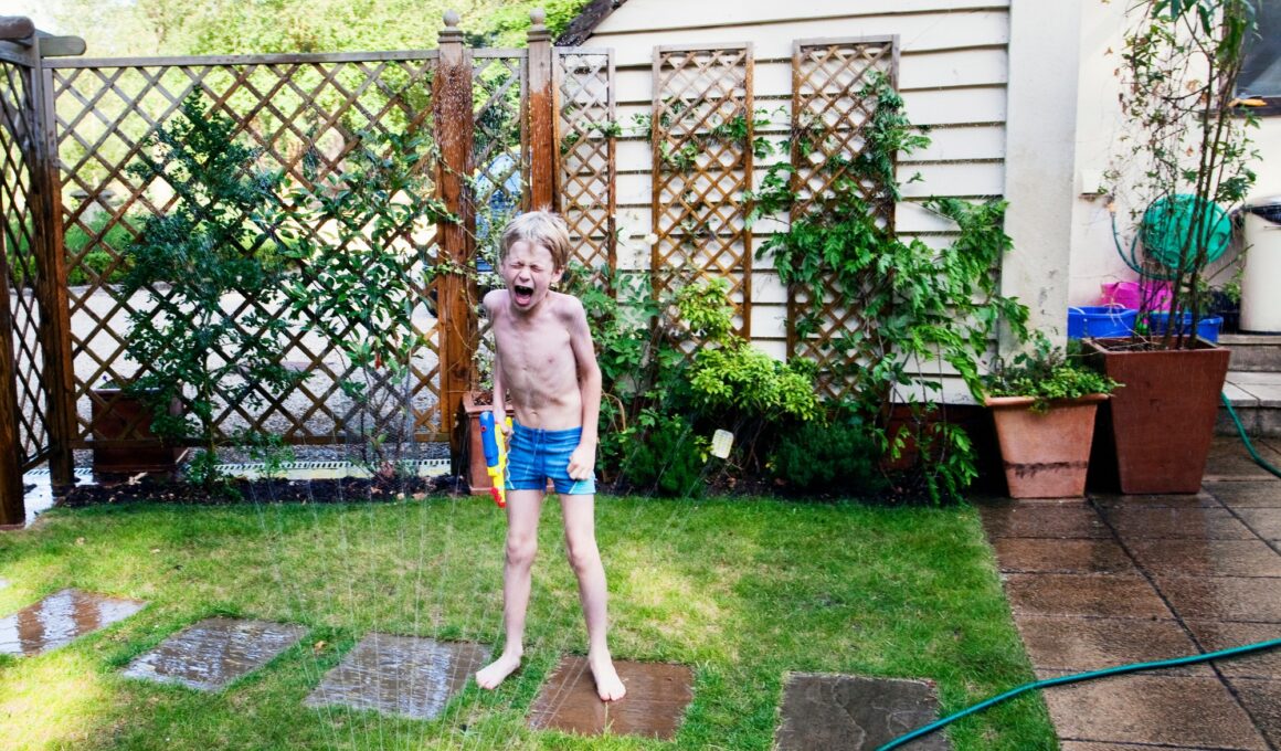 Boy playing in sprinkler in backyard