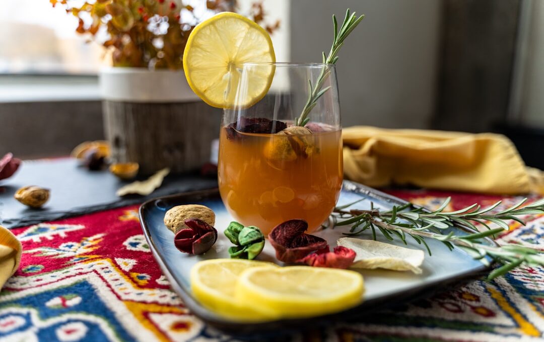 a glass with a drink and fruit on a table
