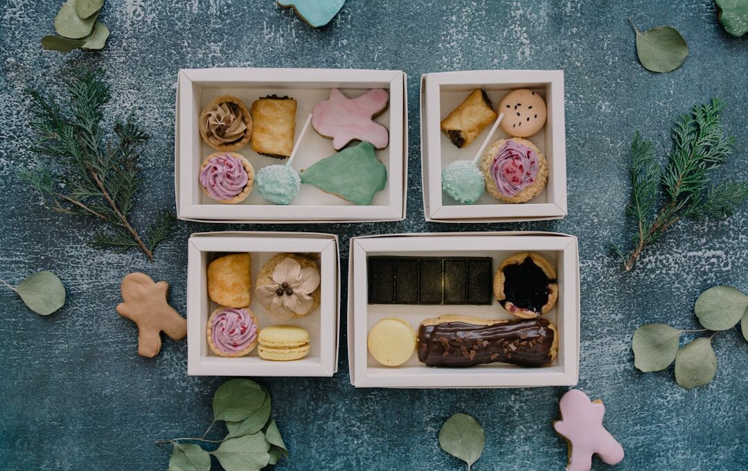 Four small boxes filled with different types of pastries