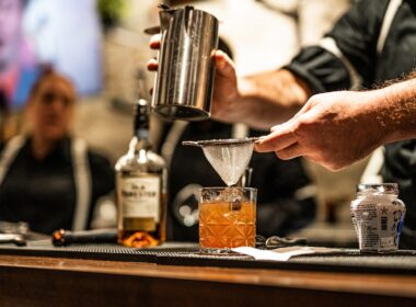 a person pouring a drink into a glass