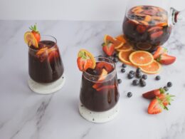 two glasses filled with liquid and garnished with fruit