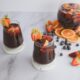 two glasses filled with liquid and garnished with fruit