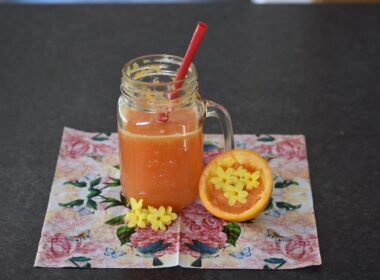 a glass of orange juice next to an orange slice