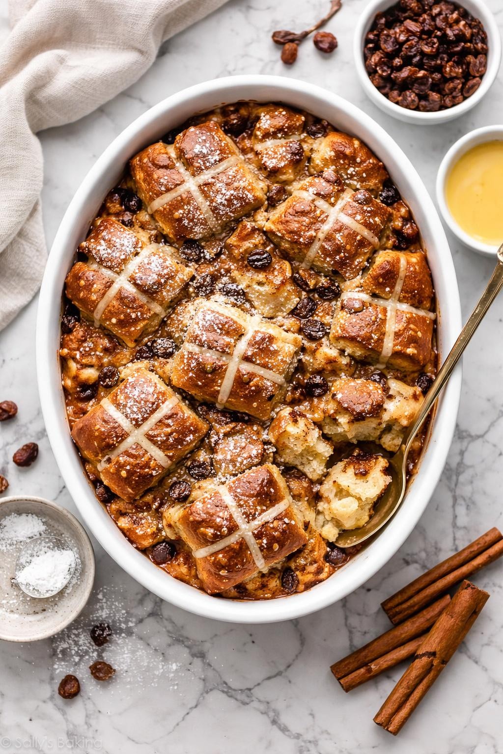 An overheard picture view of a plate of Sourdough Hot Cross Bun Bread Pudding sitting on a marble countertop table in the kitchen, professional food photography style.