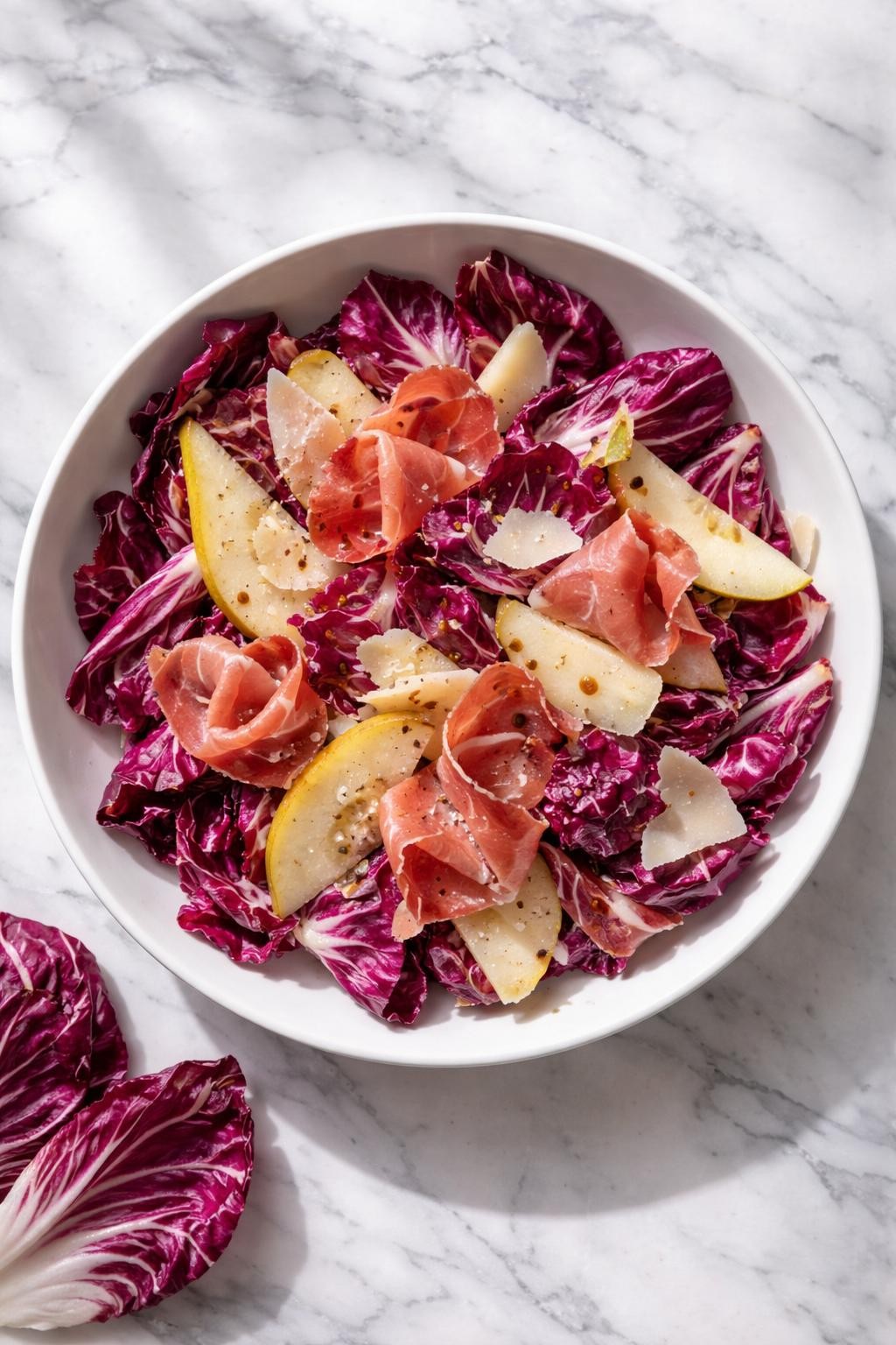 Image Prompt: Realistic top-down editorial food photography of a radicchio salad with prosciutto and parmesan in a shallow white bowl on a clean white and gray marble countertop, torn radicchio leaves with ribbons of prosciutto, shaved parmesan, pear slices, and light balsamic dressing, bright natural window lighting, soft shadows, clean editorial food styling, realistic textures, no people, no hands, no text, no watermarks, no props with writing.