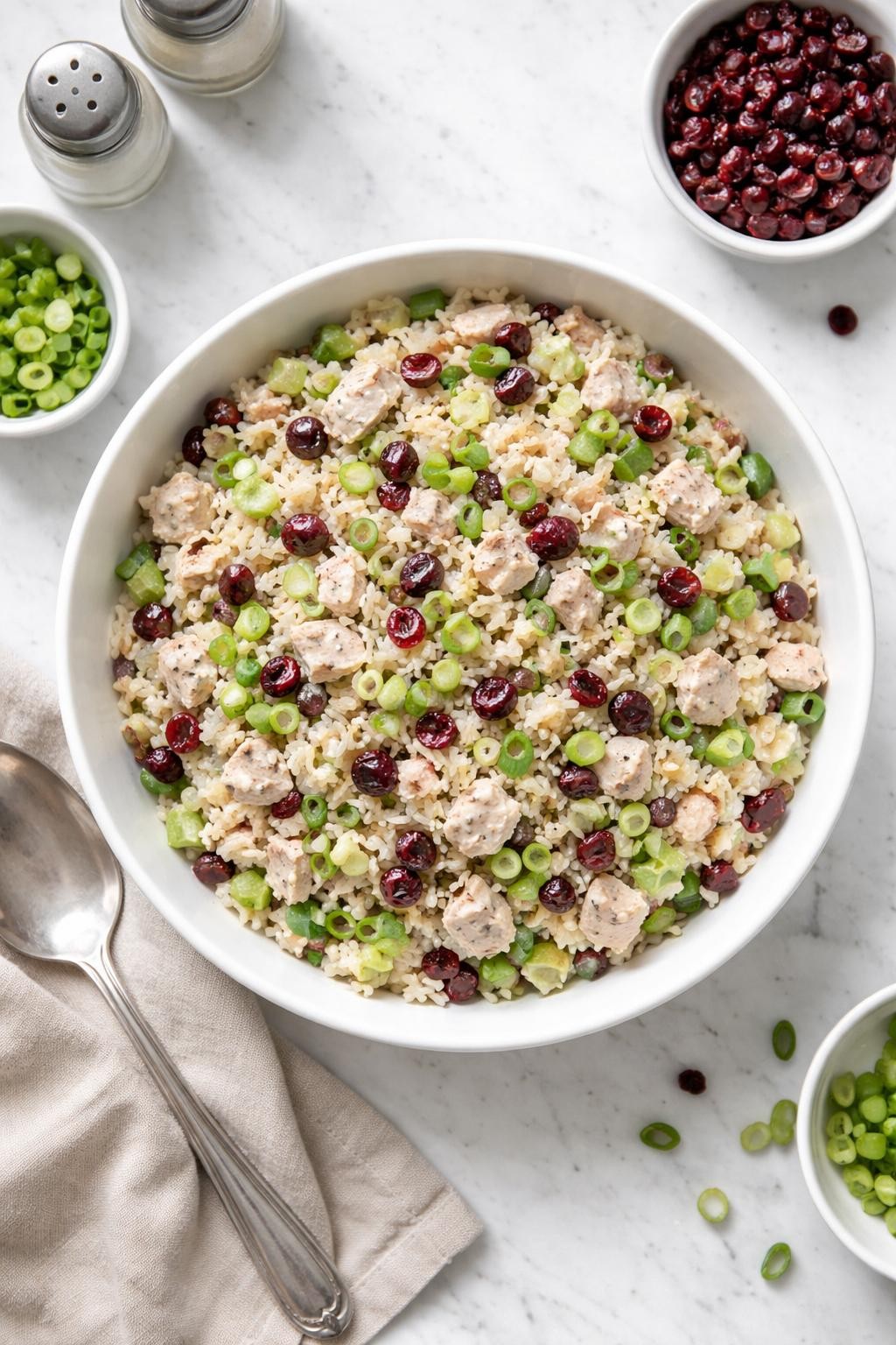 Image Prompt: Realistic top-down editorial food photography of a turkey cranberry rice salad in a white bowl on a clean white marble countertop, cold rice mixed with chopped turkey, dried cranberries, celery, green onions, and light creamy dressing, simple homemade meal prep styling, bright natural daylight, soft shadows, clean editorial composition, high detail, realistic texture, no people, no hands, no text, no watermarks, no props with writing.