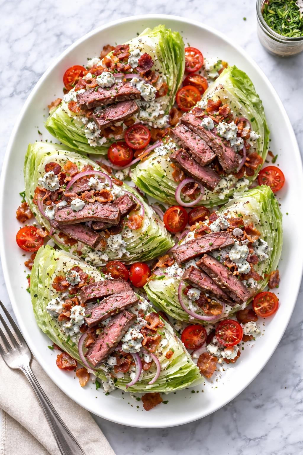 Image Prompt: Realistic top-down editorial food photography of a steak wedge salad on a marble countertop, crisp iceberg wedges topped with sliced steak, cherry tomatoes, bacon crumbles, blue cheese dressing, red onion, and blue cheese crumbles, plated neatly on a white serving platter, bright natural light, soft shadows, realistic textures, clean editorial food styling, no people, no hands, no text, no watermarks, no props with writing.