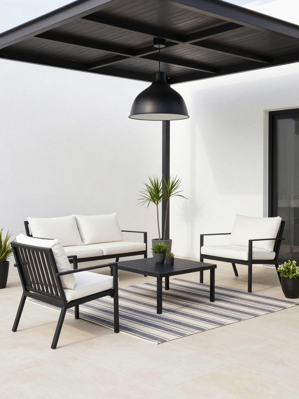 Image Prompt: A chic covered patio with black metal furniture, white cushions, black pendant light, pale tile floor, striped outdoor rug, simple potted plants, clean high-contrast modern patio style, no people, realistic DSLR image, no text, (no watermarks on images)
