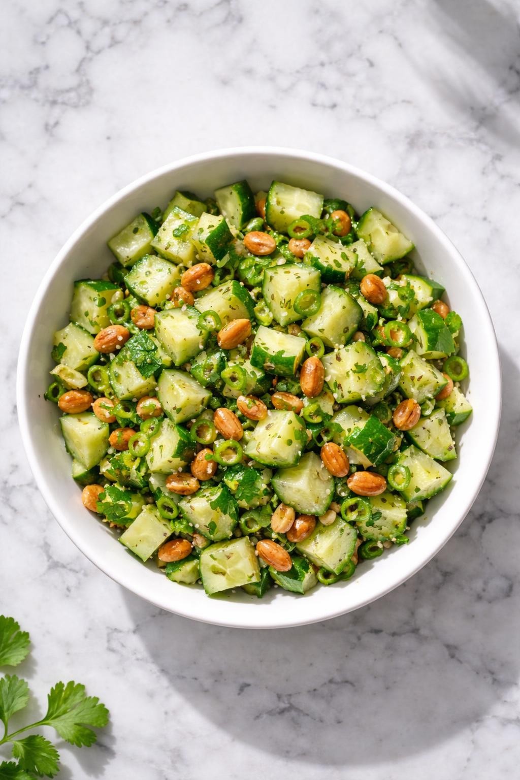 Image Prompt: Top-down realistic editorial food photography of peanut cucumber salad in a simple white bowl on a clean white and gray marble countertop, chopped cucumber mixed with roasted peanuts, cilantro, lemon juice, and green chili, crunchy homemade Indian salad styling, bright natural light, soft shadows, high detail, no people, no hands, no text, no watermarks, no props with writing.